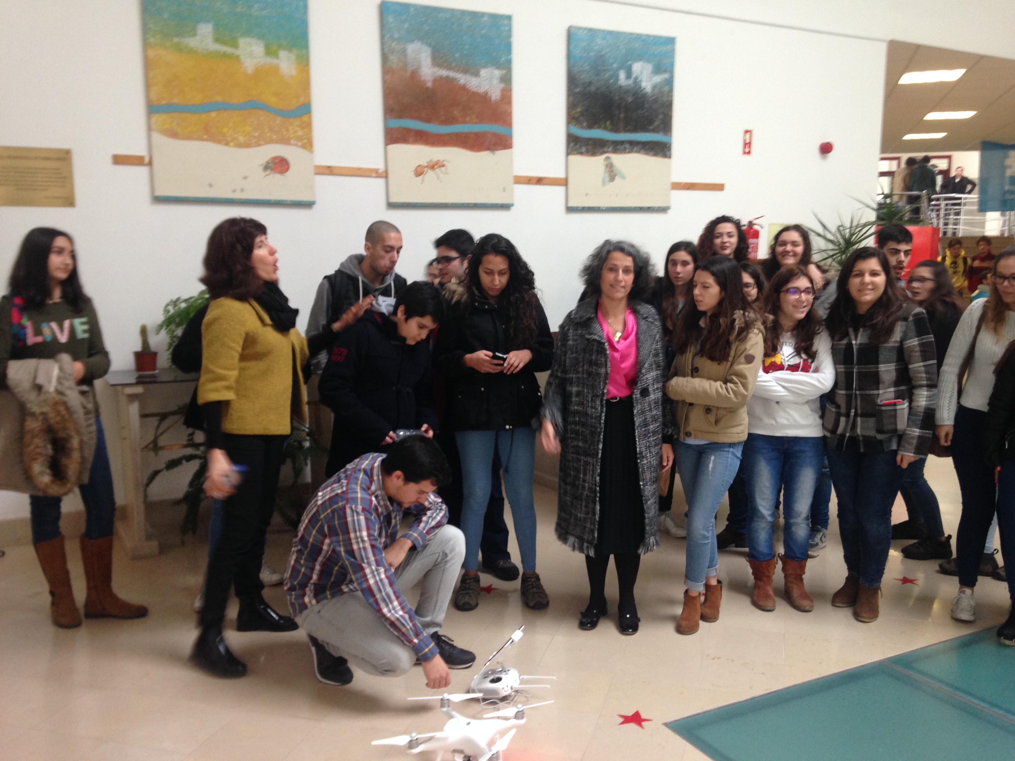 Turma reunida em volta de um drone no átrio da escola